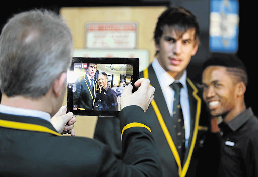 CLEARER PICTURE: Springbok coach Heyneke Meyer takes a photo of lock forward Eben Etzebeth and a fan at OR Tambo airport after team members arrived back from their successful European tour yesterday