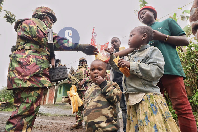 KDF Soldiers sharing some of the food stuffs they carried with the villagers at Kibumba 2 area in Goma