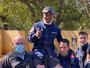 Pako Mondleke of Fire Ops SA is held up high after his long efforts hanging upside down underground to save a trapped dog from a stormwater drain ended happily.