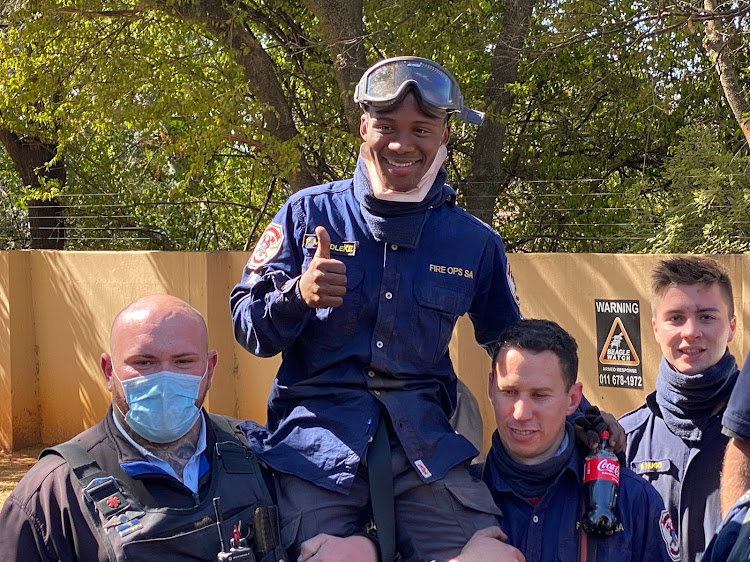 Pako Mondleke of Fire Ops SA is held up high after his long efforts hanging upside down underground to save a trapped dog from a stormwater drain ended happily.