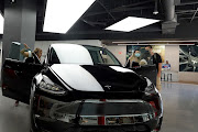 People look at a Tesla Model Y electric vehicle on a showroom floor at the Miami Design District in Miami, Florida.