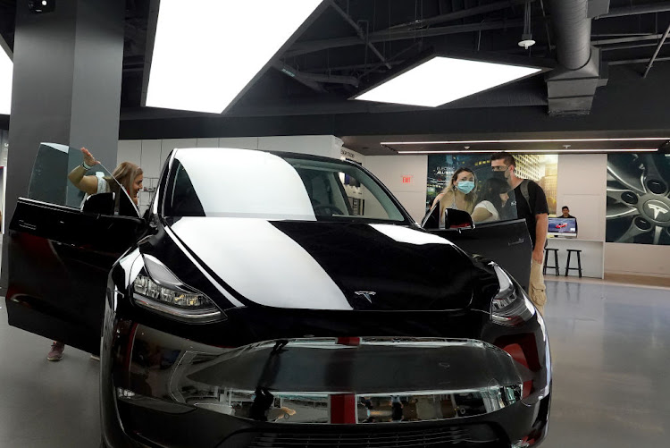 People look at a Tesla Model Y electric vehicle on a showroom floor at the Miami Design District in Miami, Florida.