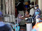 A mother with her child strapped to her back is led out of the Methodist church in Cape Town after police stormed the building.