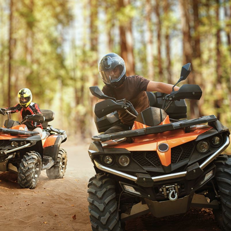 Two atv riders, speed race in forest, front view