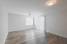 Living room with sliding glass patio door with blinds, window, wood plank floors, and a ceiling fan