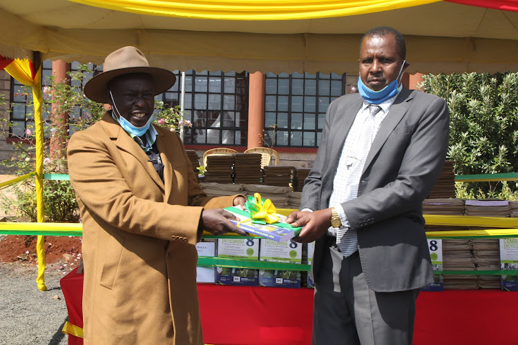 Mathira MP Rigathi Gachagua hands over a revision book to Macharia Ngatia, a head teacher, during the launched of the distribution of the books on Monday