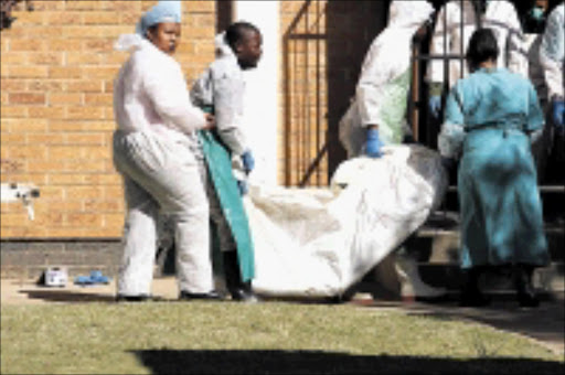 GRIM TASK: Rescue workers load miners' bodies into mortuary vans. circa June 2009. © Unknown.