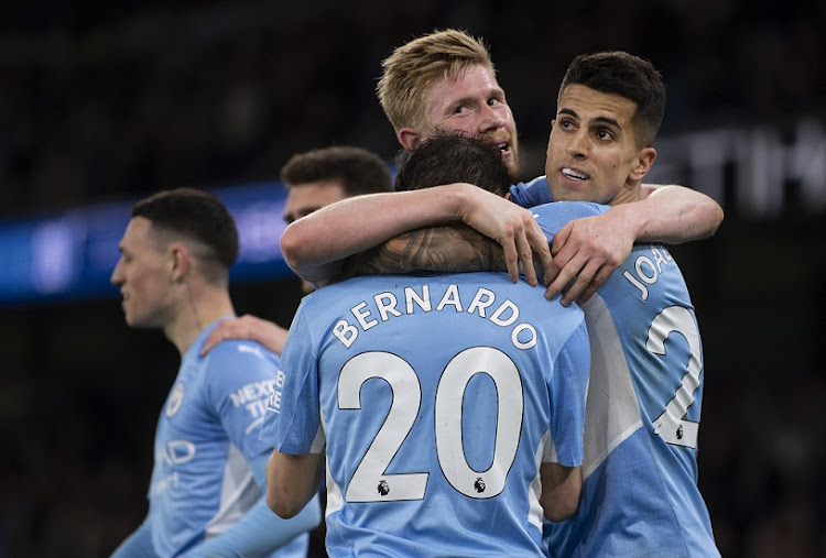 Bernardo Silva of Manchester City celebrates scoring the third goal with team mates Kevin De Bruyne and Joao Cancelo during the Premier League match against Brighton & Hove Albion at Etihad Stadium in Manchester on April 20 2022.