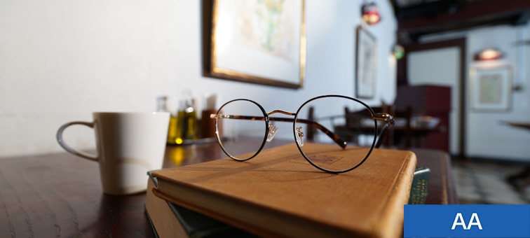 Close-up image of a book and glasses on a table