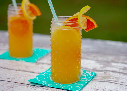 Orange lemonade poured over ice with an orange slice garnish.