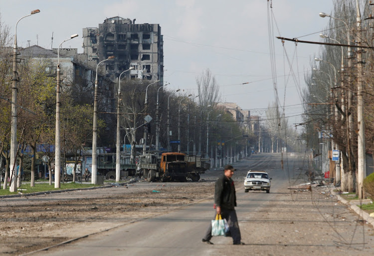 A local resident crosses a street damaged during Ukraine-Russia conflict in the southern port city of Mariupol, Ukraine April 15, 2022.