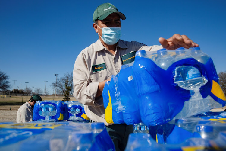 Ramiro Guerra, a Dallas Parks and Recreation employee, picks up a case of water to hand out at a distribution site after winter weather caused electricity blackouts and water service disruption in Dallas, Texas, US February 23, 2021.