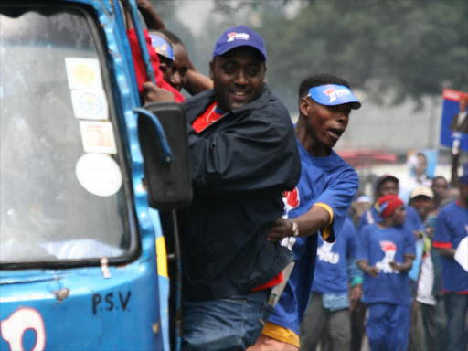 Matatu touts hang on the door a matatu. /FILE