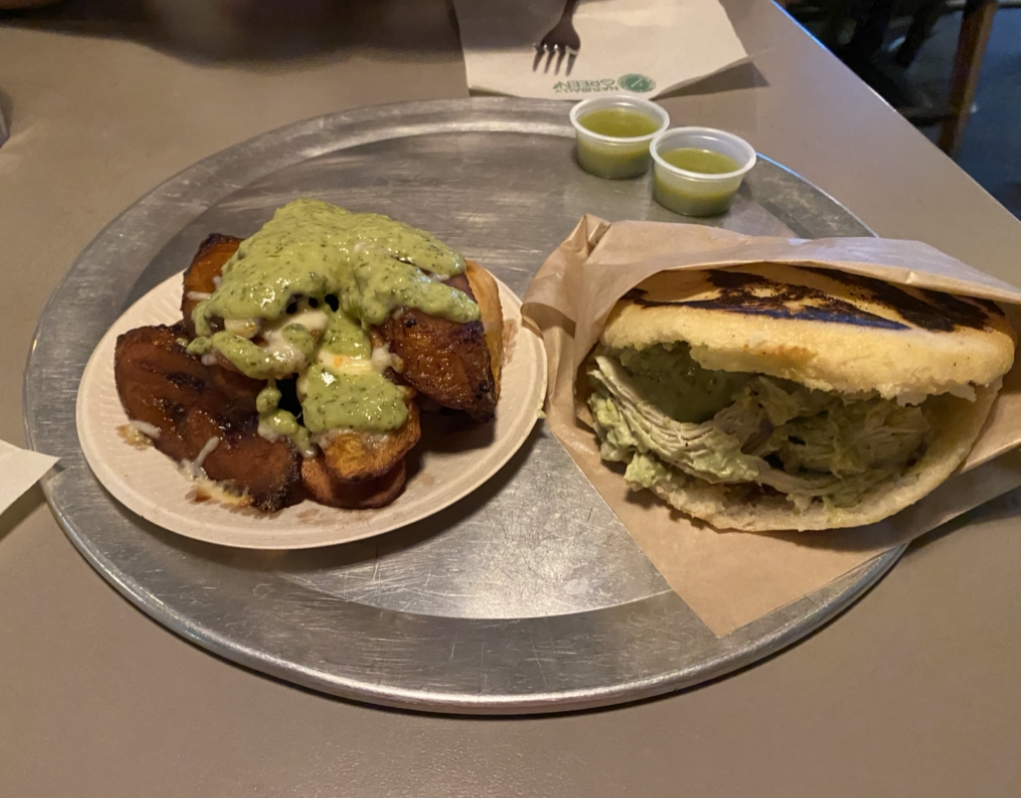 Sweet plantains with savory sauce and cheese on left. Reina arepa (chicken, guac, green sauce) on right.