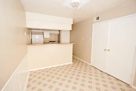 Dining area adjacent to kitchen with tan walls and tan diamond designed linoleum