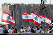 People carry national flags near the site of last year's Beirut port blast, as Lebanon marks the one-year anniversary of the explosion in Beirut, Lebanon on August 4 2021. 