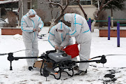 Workers in protective suits prepare a drone amid the snow to disinfect a residential compound under lockdown, following the Covid-19 outbreak in Changchun, Jilin province, China, on March 14,2022.  