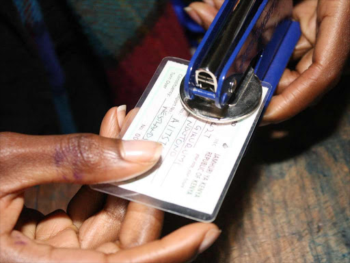 An IEBC clark stamps a voter card after registration of a voter. Voting is a constitutional right to all eligible citizens.