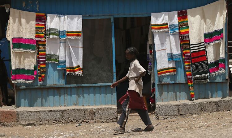 A girl walks past a shop selling traditional textiles near the Lalibela holy sites on March 19, 2013 in Lalibela, Ethiopia.