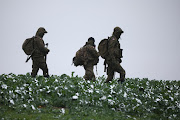 Polish soldiers walk in the field near the site of an explosion in Przewodow, a village in eastern Poland near the border with Ukraine, November 17, 2022. 