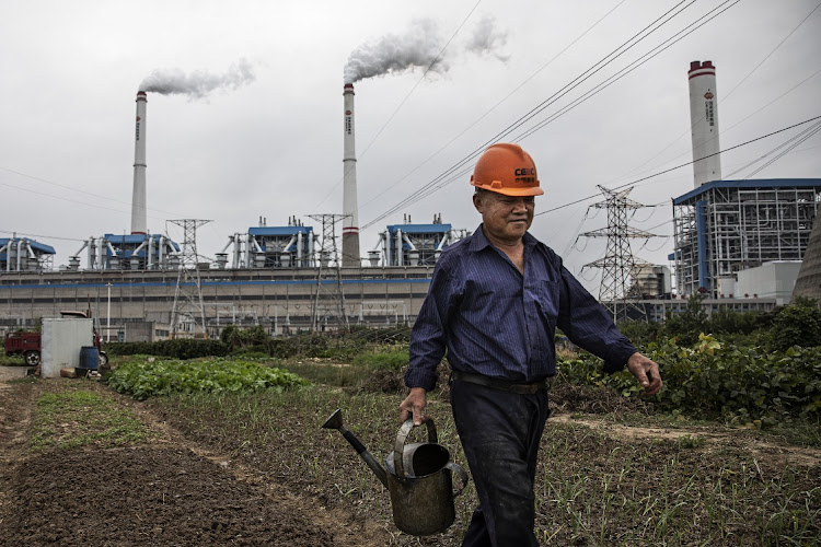 A man is seen watering plants in front of a coal fired power plant in Hanchuan, Hubei province, China, on October 13 2021. Picture: GETTY IMAGES