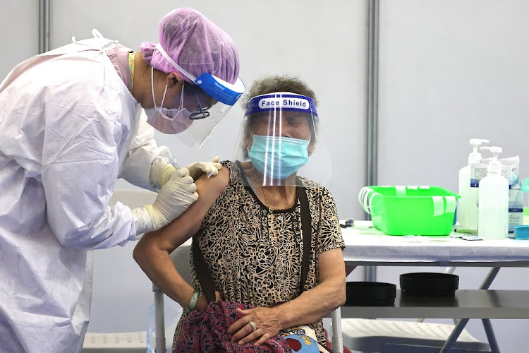 A medical worker administers a dose of the AstraZeneca vaccine against the coronavirus disease (COVID-19) to a woman during a vaccination session for elderly people over 85 years old, at an auditorium in New Taipei City, Taiwan June 16 2021.