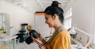 Nasmejana ženska, ki uporablja fotoaparat DSLR