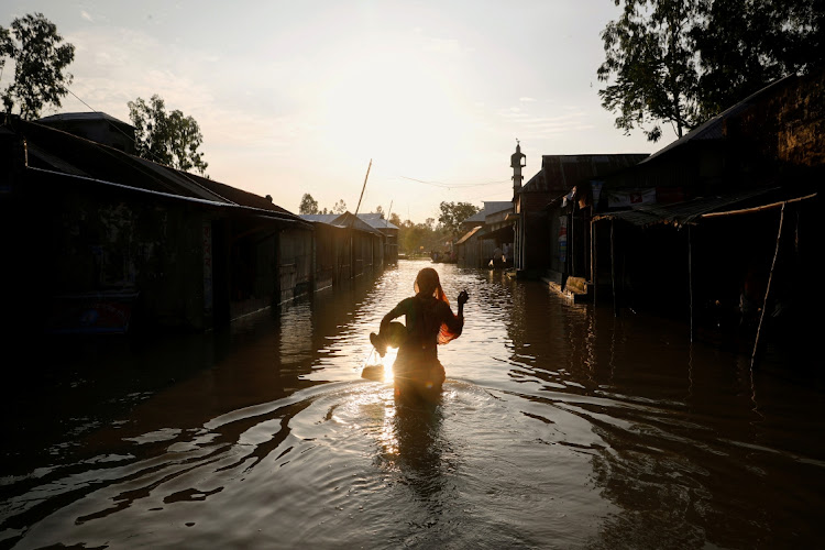 A woman is silhouetted as she walks on a flooded road in Jamalpur, Bangladesh during seasonal flooding, July 18, 2020. Picture: MOHAMMAD PONIR HOSSAIN/REUTERS