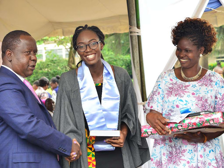 Interior Cabinet Secretary, Dr. Fred Matiang'i awards the top KCSE 2018 student Irine Juliet Otieno for her exemplary performance in the company of her mother Mary Achieng Otieno at Pangani Girls on June 7, 2019.