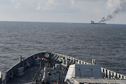 Indian Navy's guided missile destroyer INS Visakhapatnam responds as smoke rises from Marlin Luanda, merchant vessel, after the vessel was struck by a Houthi anti-ship missile, at the location given as Gulf of Aden, in this handout picture released January 27, 2024.