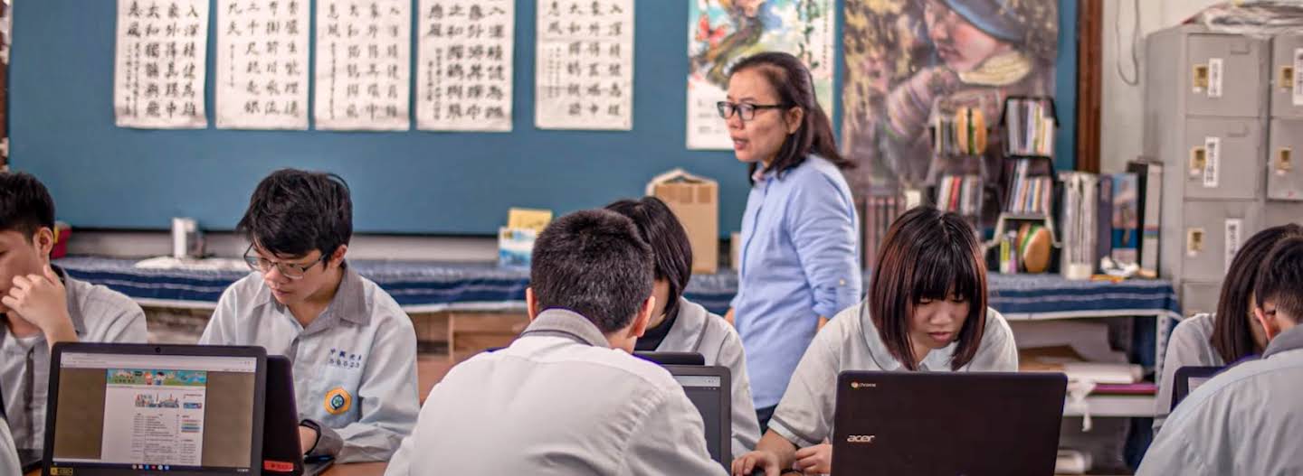 A female teacher walking through a classroom full of students using their Chromebooks.