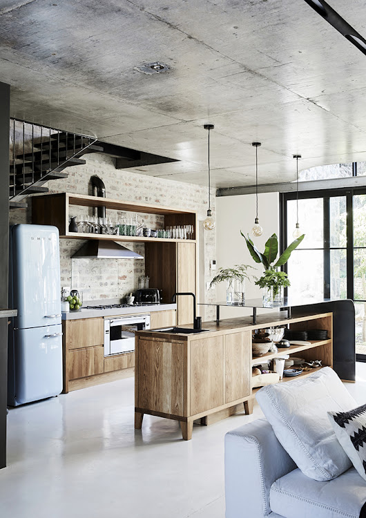 The oak kitchen island features a tempered steel top while a pop of baby blue from the Smeg fridge.