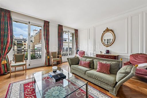 Living room with green sofa and urban view - Apartment purchase in Paris 16ème, 7 rooms, 4 bedrooms