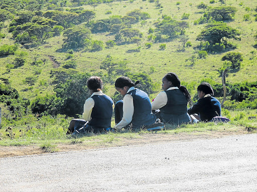 Pupils from Tsholomnqa High School sit resignedly on the side of the road, hoping for a lift to school, after their scholar transport failed to arrive