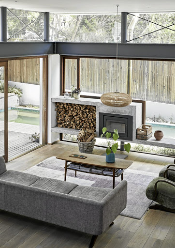 The concrete fireplace is set in a wall of glass blurring the boundaries between indoor and out.