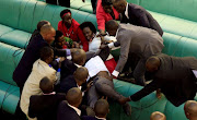 Ugandan opposition lawmakers fight with plain-clothes security personnel in the parliament while protesting a proposed age limit amendment bill debate to change the constitution for the extension of the president's rule, in Kampala, Uganda September 27, 2017. 