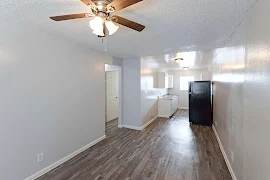 Living area with wood-inspired flooring, gray walls, white trim, ceiling fan, and view of the kitchen 