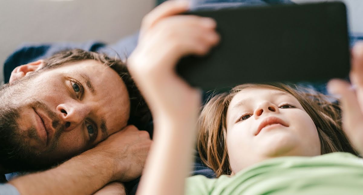 Een vader en zoon bekijken samen een video op een telefoon.