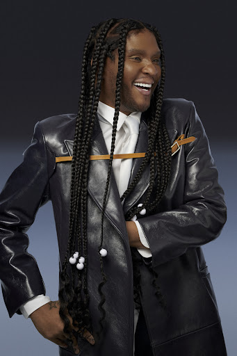 Law Roach in a black trench coat smiling.