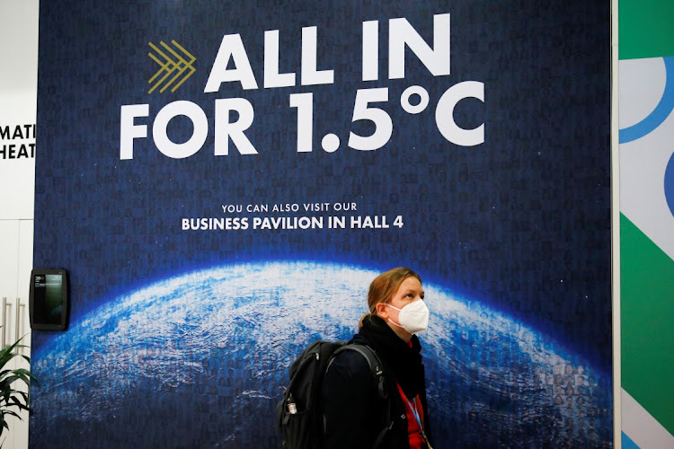 A delegate walks past a climate change poster at the UN Climate Change Conference (COP26) in Glasgow, Scotland, Britain, on November 1 2021. Picture: REUTERS/PHIL NOBLE