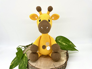 crochet giraffe sitting up on wooden surface