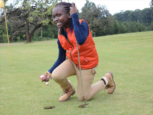 Joan Chepkemoi Chesosi 9, a Junior Golfer, picking up a ball from a hole during a golf event at the Kitale Club / CORAZON WAFULA