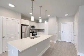 Kitchen with plank flooring, white cabinets, white quartz countertops, and stainless steel appliances