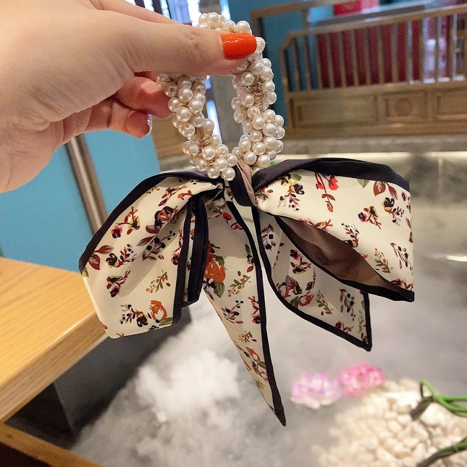 Haarring met strik, parel en elastiek voor dames, een stijlvol accessoire voor chique paardenstaarten en andere kapsels.
