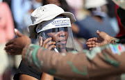 A woman wears a protective face shield during food distribution in Diepsloot near Johannesburg, South Africa.