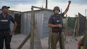 A Metro Police officer signals to other members of the Neighbourhood Safety Team during a raid in Blikkiesdorp. 