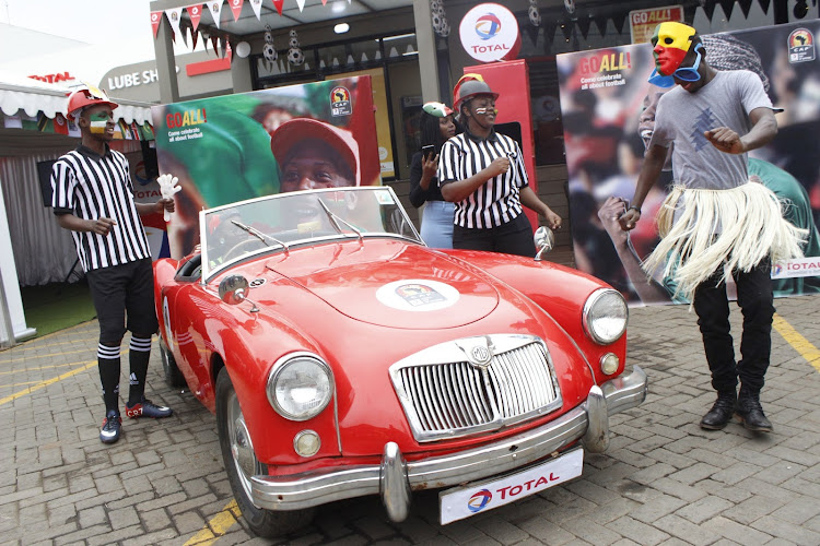 Total Kenya staff dance besides a Total branded vintage car