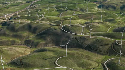 Green rolling hills dotted with wind turbines