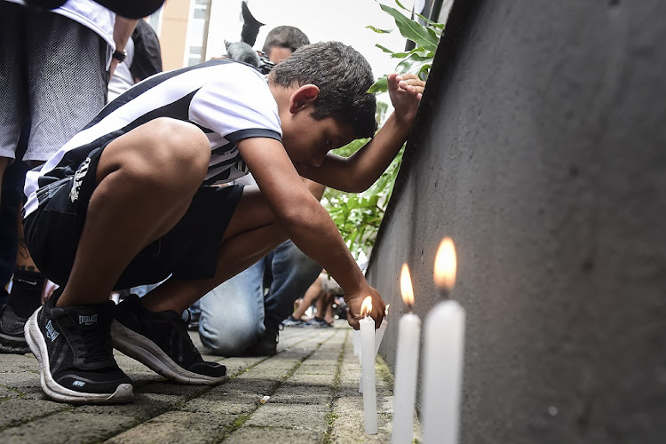 A youth lights a candle as fans hold a vigil on December 4 2022 in support of football legend Pele who remains hospitalised due to a respiratory infection amid ongoing colon cancer treatments at Albert Einstein Israeli Hospital in Sao Paulo, Brazil.