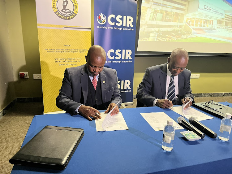 Special Investigating Unit head Andy Mothibi, left, and Council for Scientific and Industrial Research CEO Dr Thulani Dlamini sign a memorandum of understanding to enhance the use of technology to fight corruption and maladministration.